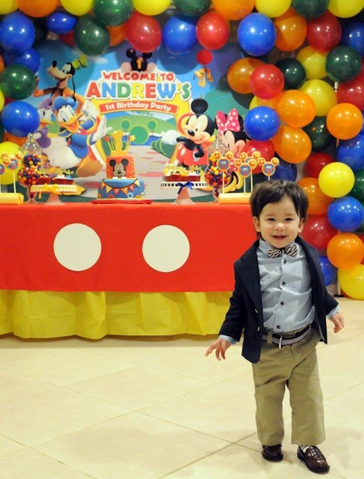 A boy stands in front of his birthday party decorations
