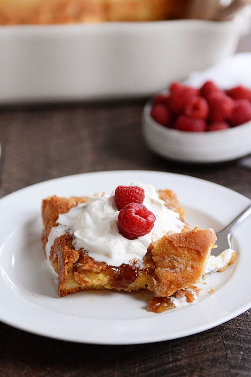 white plate of french toast topped with white cream and raspberries