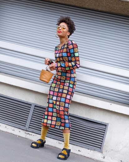 A woman posing in a colorful midi dress and sport sandals