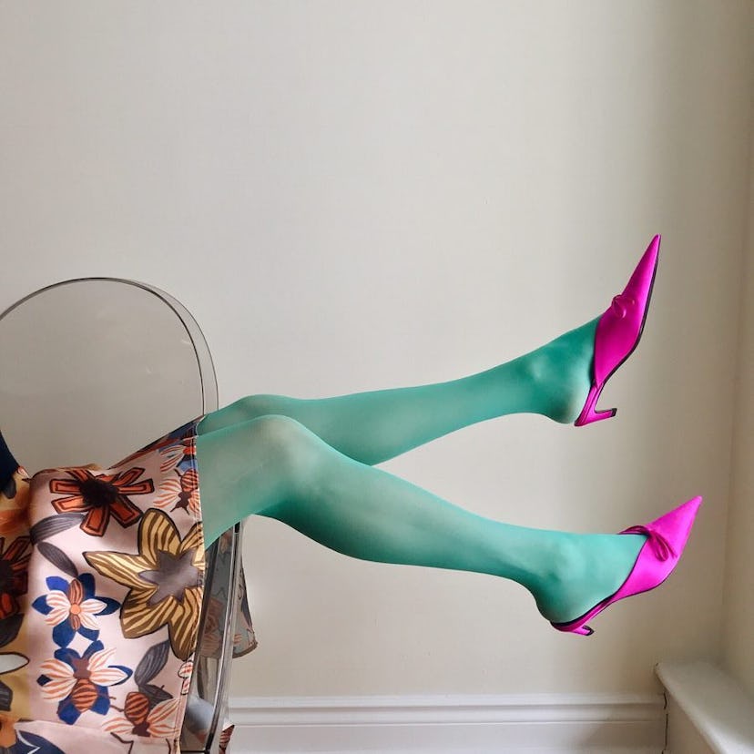 A woman wearing green opaque tights paired with magenta heels and floral skirt