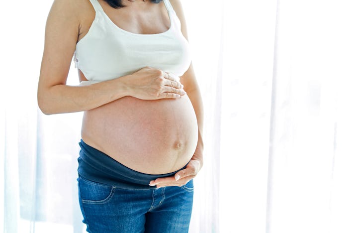 A petite pregnant woman in Amazon-available maternity jeans for petite women