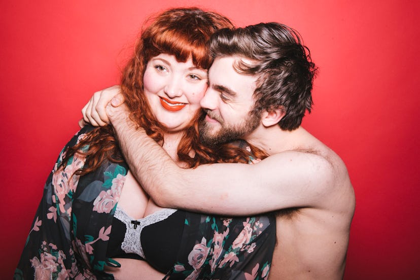 A man hugging his female partner, while she is smiling