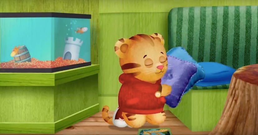 Daniel Tiger holding a pillow while standing next to aquarium 