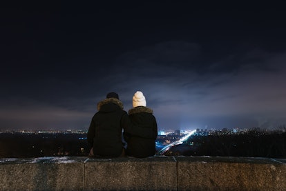Two introverted people sitting and watching city lights in the distance
