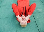 A man laying on the ground, holding his head because of chronic migraine.
