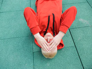 A man laying on the ground, holding his head because of chronic migraine.