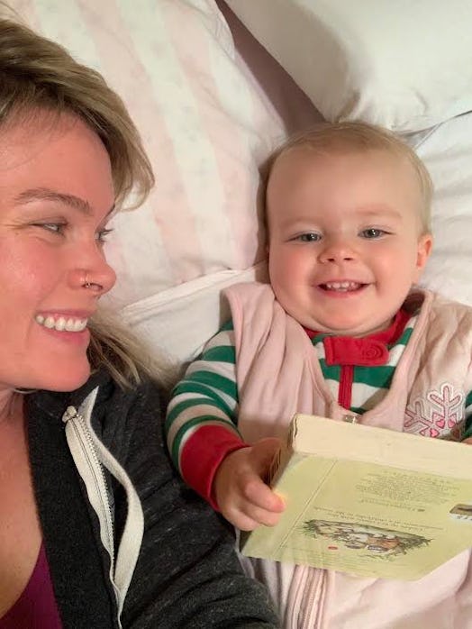 Mom taking a selfie with her little daughter while she is holding book and smiling