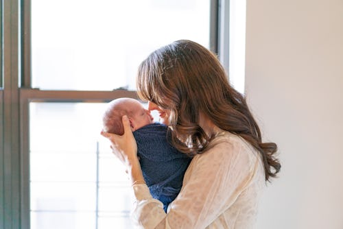 A mother hugging and kissing her newborn baby