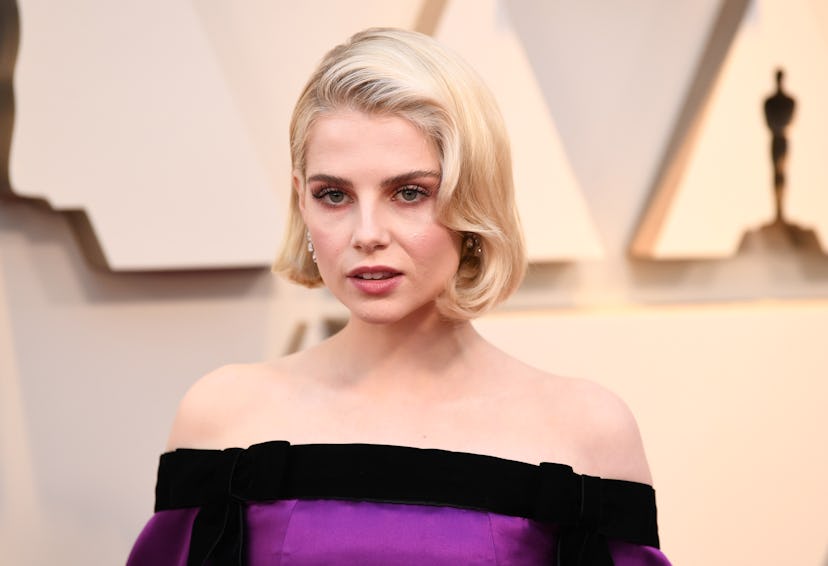 Lucy Boynton with a muted-pink smoky eye, glossy lips and soft, wavy blonde hair, wearing a straples...