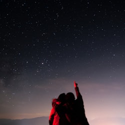 Two people hugging and looking up at the starry night sky