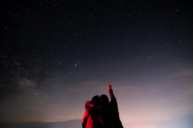 Two people hugging and looking up at the starry night sky