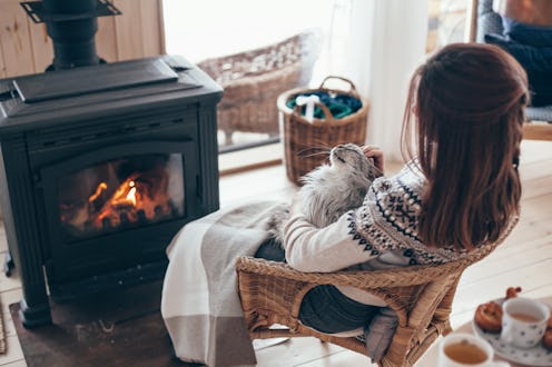 A woman with dark brown hair, covered with a blanket while sitting with her back turned in front of ...