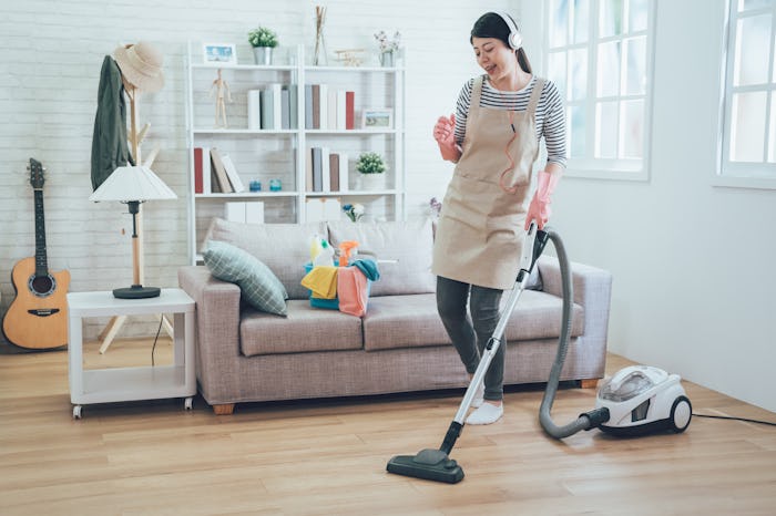 Woman vacuuming her home while wearing an apron