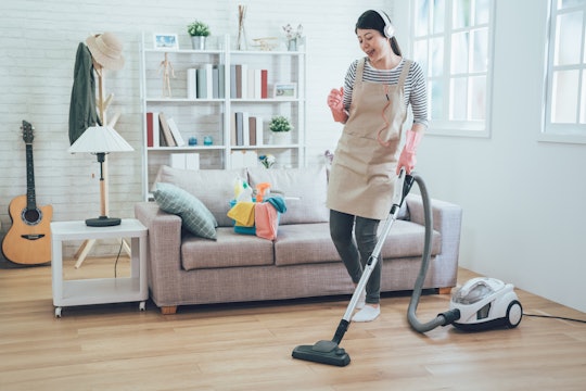 Woman vacuuming her home while wearing an apron