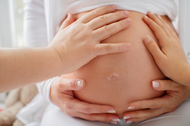 People touch the belly of a surrogate mother.