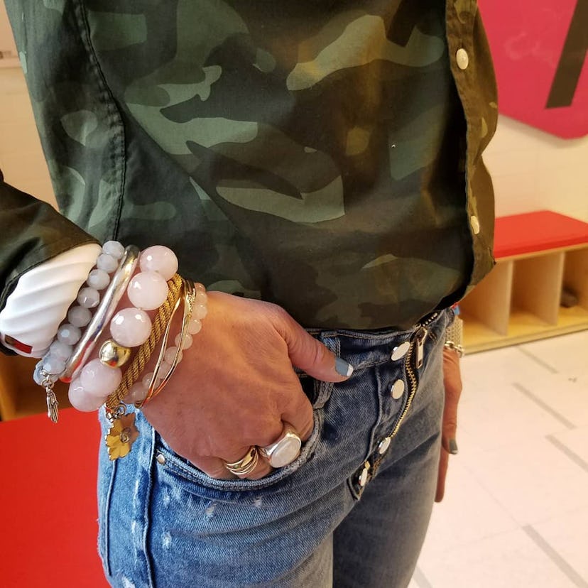 Jacqui Getz wearing a camouflage shirt, denim jeans, and bead bracelets in different colors and size...