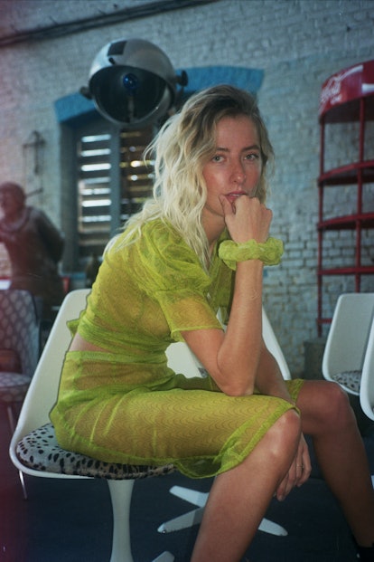 A blonde girl posing in a slime green see-through dress 