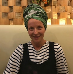 Rachel Fleit with a head scarf, in a stripy shirt and black overalls