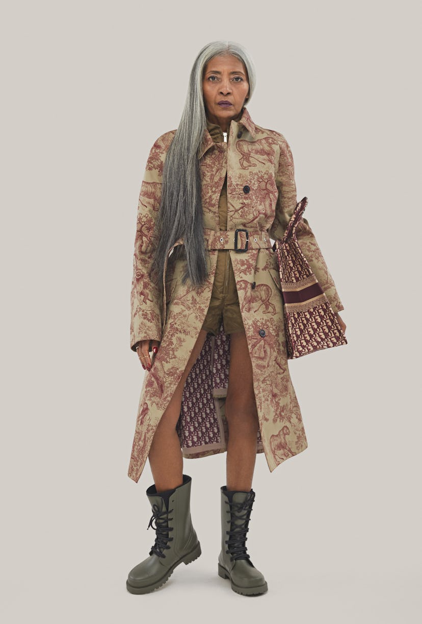 An old female model posing in a light brown coat with burgundy animal drawings