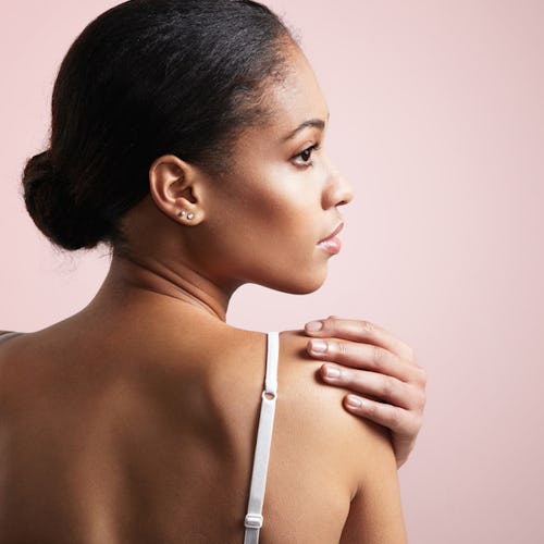 A woman with a low bun applying squalane oil with beauty benefits 