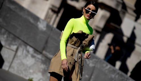 A woman wearing a slime green turtleneck and a brown skirt
