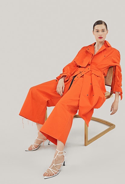 A female model posing in an orange combination of a blazer and pants