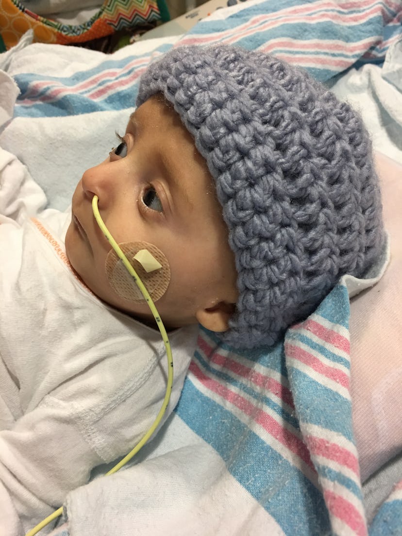 A baby at the NICU with a blue knit beanie and a breathing tube