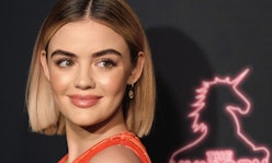 Lucy Hale with her hair in a bob wearing an orange dress at a red carpet event