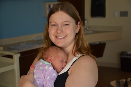 A woman that is experiencing postpartum anxiety, holding her baby close to her chest 