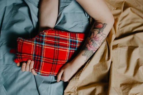 A woman holds a hot water bottle to get rid of period cramps at night.
