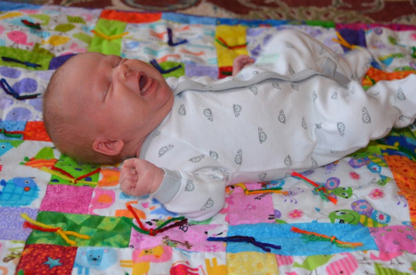 A little baby lying on a colorful blanket