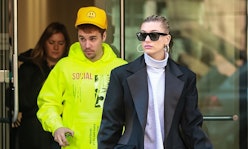 Hailey Baldwin in a leather jacket and purple turtleneck in front of justin bieber in a yellow hoodi...