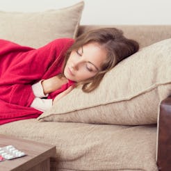 A woman lying on her bed covered with a blanket and meds in front of her for her weakened immune sys...