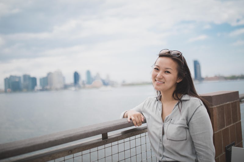 Sabrina Qiao, diagnosed with a chronic autoimmune disease standing next to a river with the NYC in h...