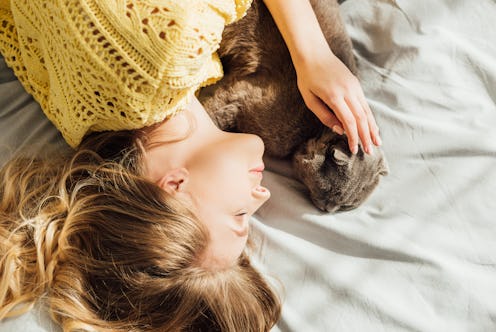 A young woman with a struggling immune system wearing a yellow sweater while lying on a bed with her...