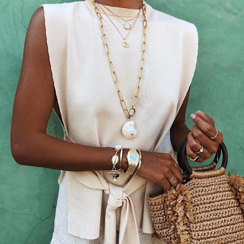 Julie Sarinana wears a white belted dress accessorized with shell jewelry.