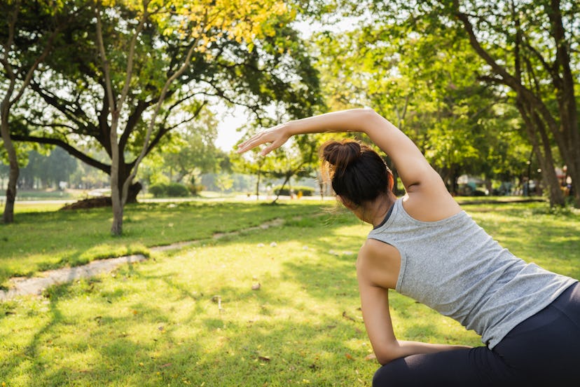A woman in her gym clothes doing yoga in a park