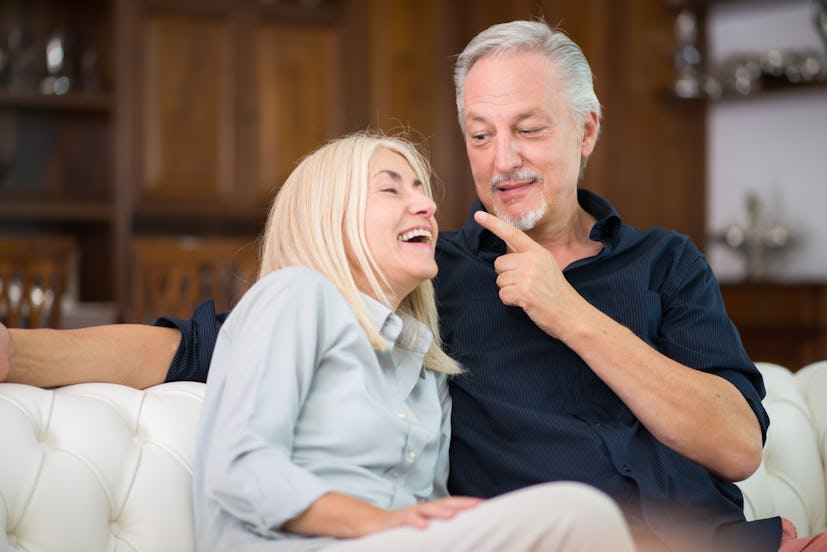 An older couple sitting on a couch and laughing