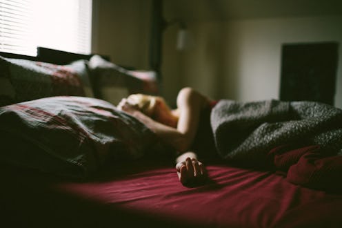 Tired woman lying down in her bed while suffering from endometriosis pain