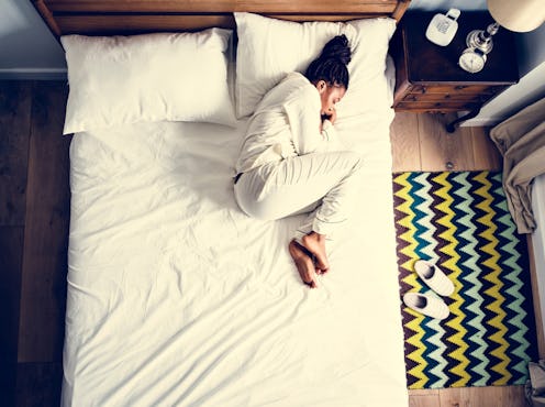 A woman living with endometriosis curled up on a bed