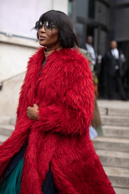 Naomi Campbell wearing a red faux fur coat and sunglasses during Paris Fashion Week