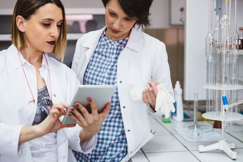 Two young women analyzing and discussing something on a tablet in the laboratory.