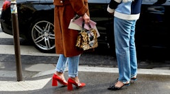Two ladies that are wearing jeans standing and wearing red and blue heels