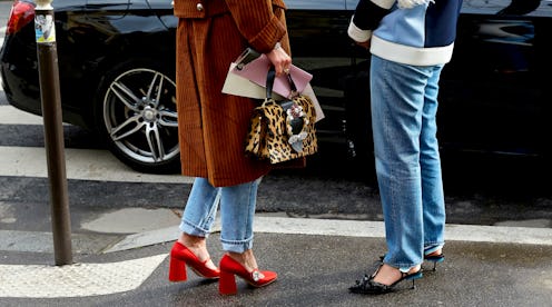 Two ladies that are wearing jeans standing and wearing red and blue heels