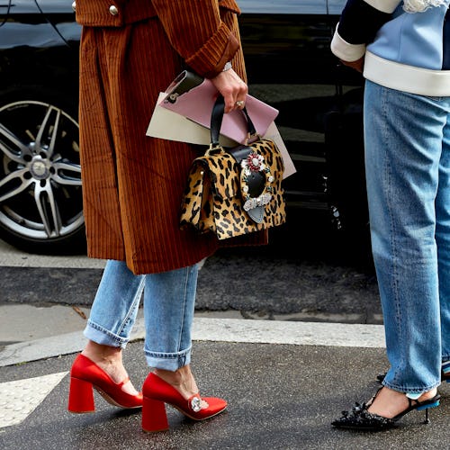 Two ladies that are wearing jeans standing and wearing red and blue heels
