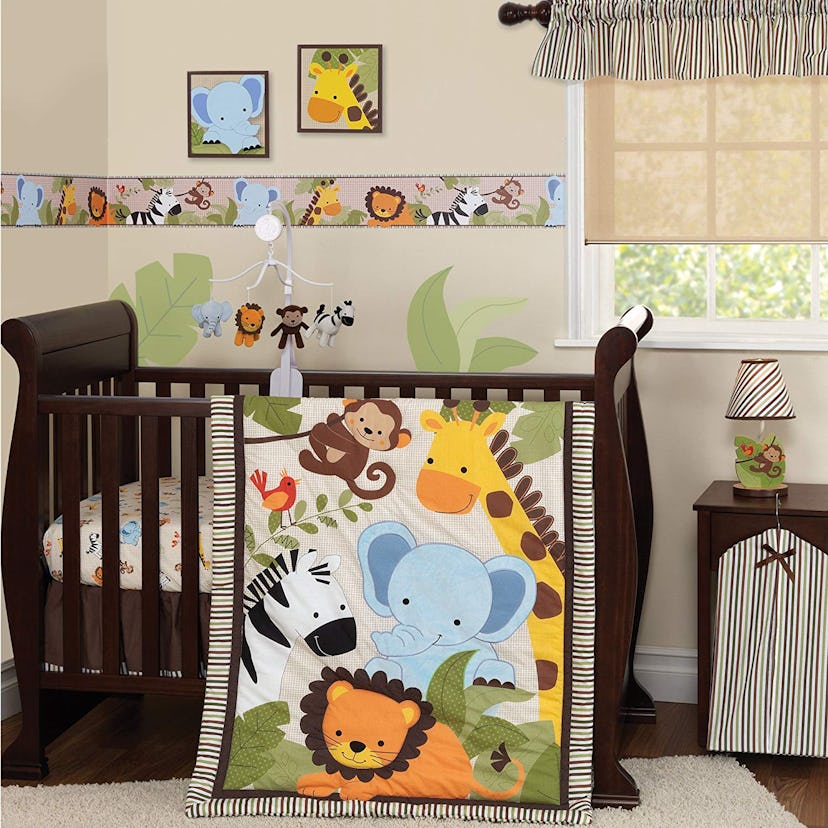 A wooden baby crib with blankets that have jungle animal drawings