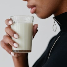 A woman holding a glass of synthetic breast milk