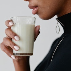 A woman holding a glass of synthetic breast milk
