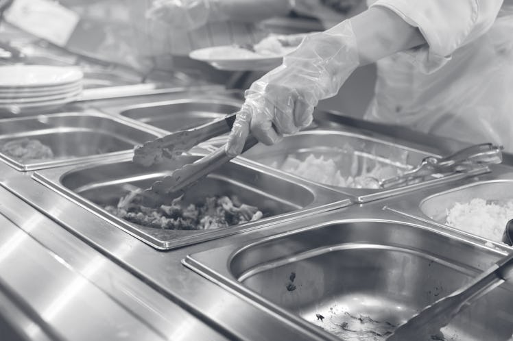 A lunch worker pulls lunch items out of the buffet line.
