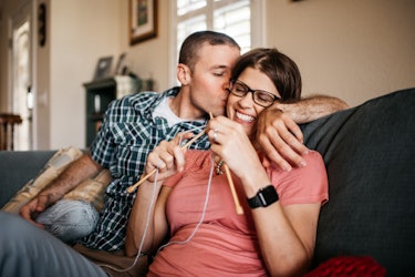 Pregnant woman with an eating disorder knitting while her partner kisses her on the cheek